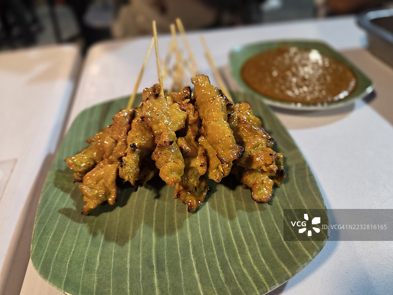 黄香料腌制的沙爹猪肉，穿在串上，烤至熟透，搭配酱汁和沙拉一起食用。图片素材