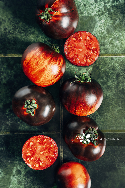 从高处俯瞰各种新鲜番茄，放在绿色瓷砖桌上。黑美人番茄和樱桃番茄。留白空间。图片素材