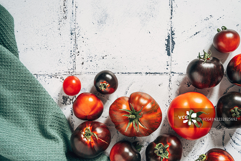 高处视角的各种新鲜番茄，放在瓷砖桌上。黑美人番茄和樱桃番茄。留白空间图片素材