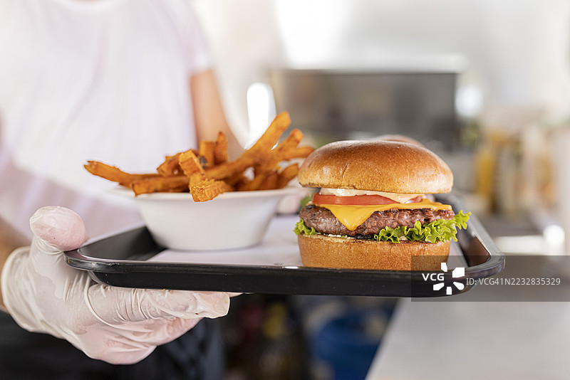 现成的汉堡和甜薯条放在食品车柜台上的托盘里。图片素材