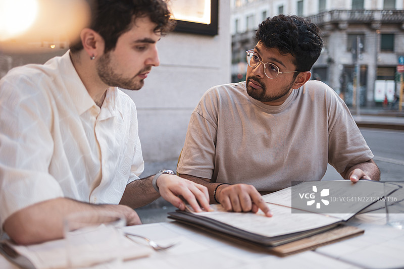 两位年轻男子在户外选择餐厅菜单图片素材