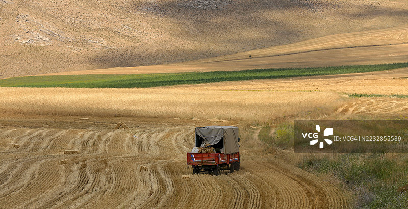 农村风景中收割后的田野上的拖拉机拖车图片素材