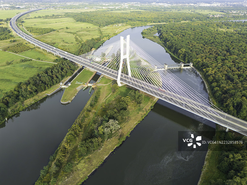 宁静的河流上方的悬索桥，周围环绕着郁郁葱葱的绿色景观图片素材