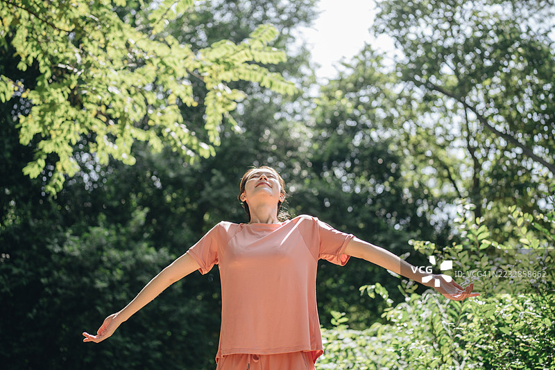 健身、运动、锻炼的快乐女子在公园里拥抱自然，享受户外的晨光，张开双臂，面带笑容，展现健康活力与身心愉悦。图片素材