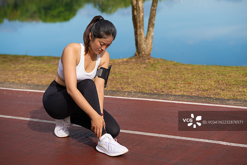 女性用手握住跟腱，因疼痛而痛苦。运动锻炼时脚踝扭伤意外，跑步时跟腱受伤。图片素材