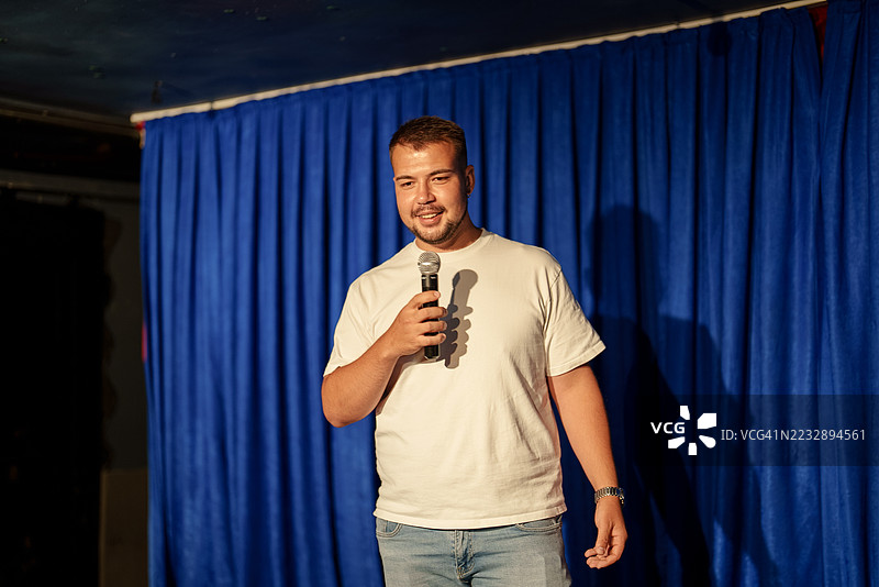 男人在舞台上手持麦克风发言。图片素材