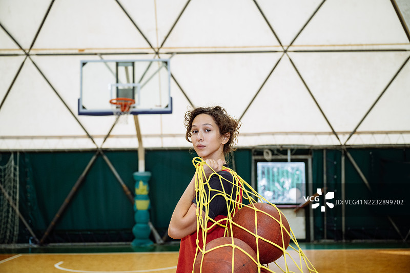 年轻自信的女性身穿运动服在室内打篮球图片素材