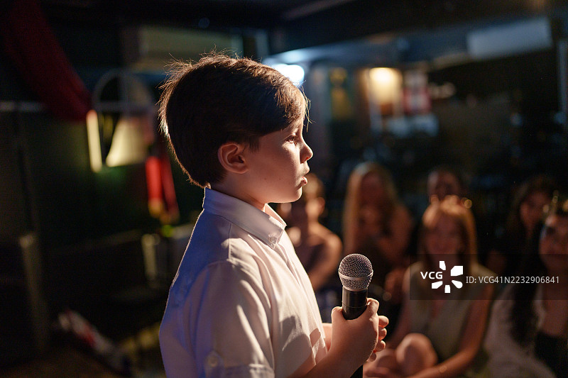 男孩在舞台上用麦克风对观众讲话图片素材