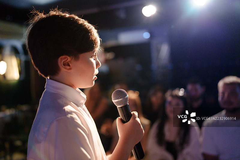 男孩在舞台上用麦克风对观众讲话图片素材