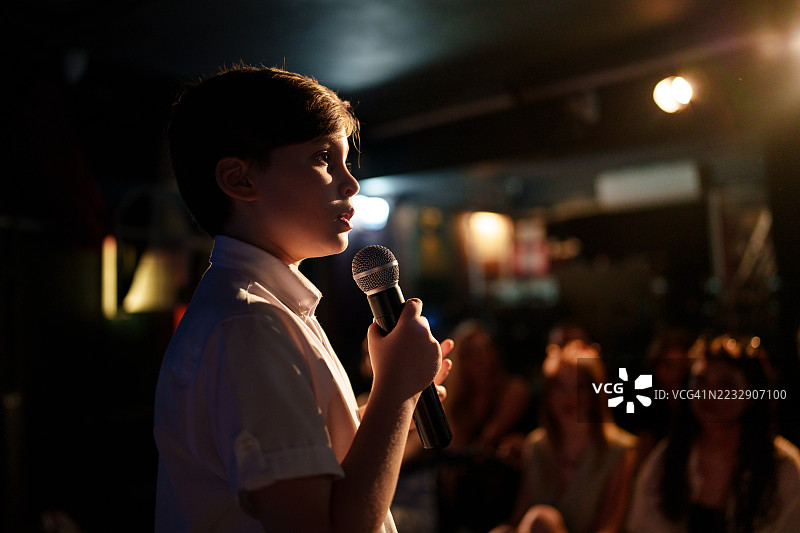 男孩在舞台上用麦克风对观众讲话图片素材