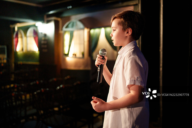 男孩在舞台上用麦克风对观众讲话图片素材
