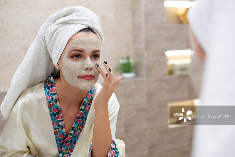 年轻快乐的女性在浴室里敷面膜图片素材