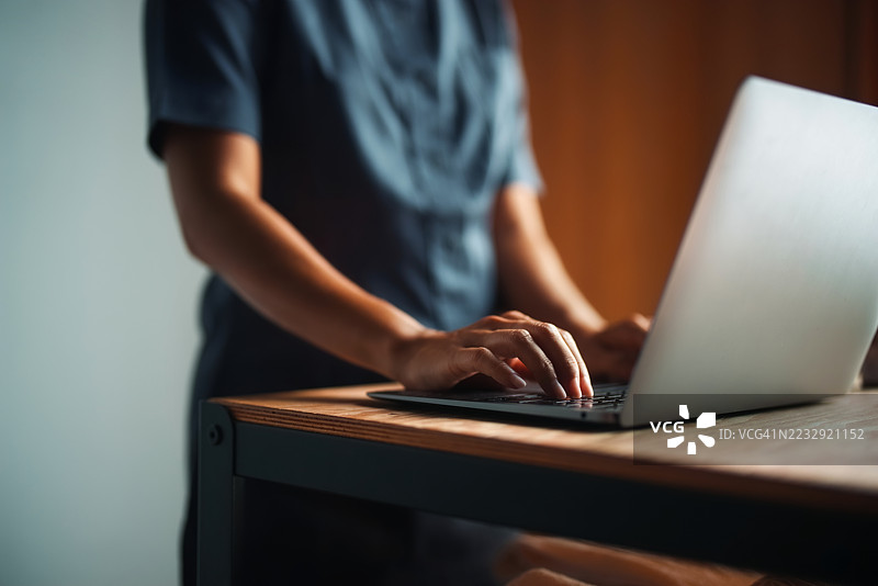 在舒适的光线下，工作站上手在笔记本电脑上打字图片素材
