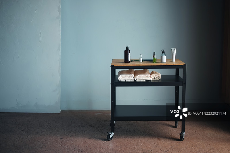 滚动推车上整齐摆放的水疗用品，包括毛巾和香薰瓶图片素材