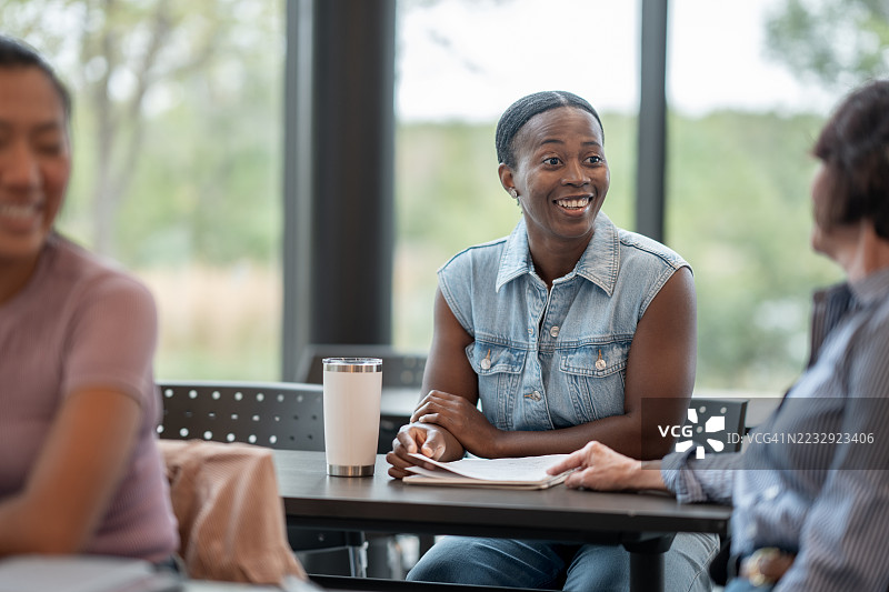 一群同事在明亮的办公室环境中分享欢笑图片素材