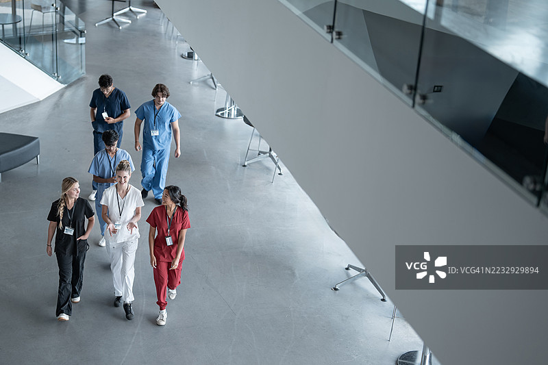 一群医学生穿着颜色编码的护士服在医院走廊里行走图片素材