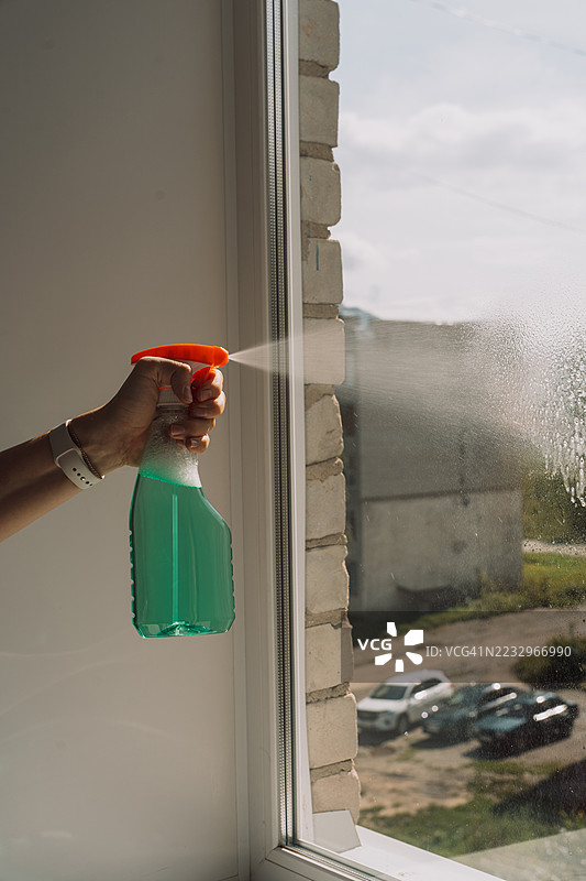 手动喷洒清洁液在窗户玻璃上图片素材