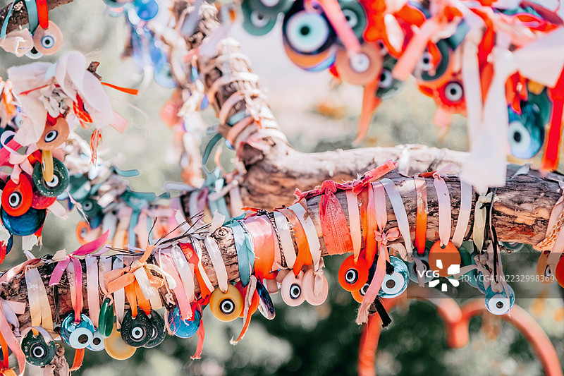 缠绕着彩色邪恶之眼护身符和丝带的树枝，背景明亮阳光。民间传说、文化传统和保护象征概念。图片素材