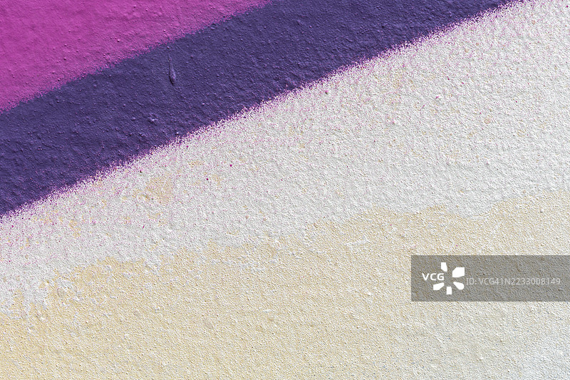 喷漆的米白色和白色墙壁上有紫色线条的宏观特写。图片素材