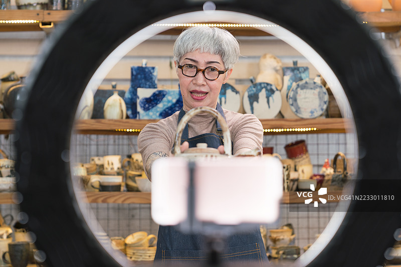 一位年长的艺术家在工艺品工作室制作视频进行销售。图片素材