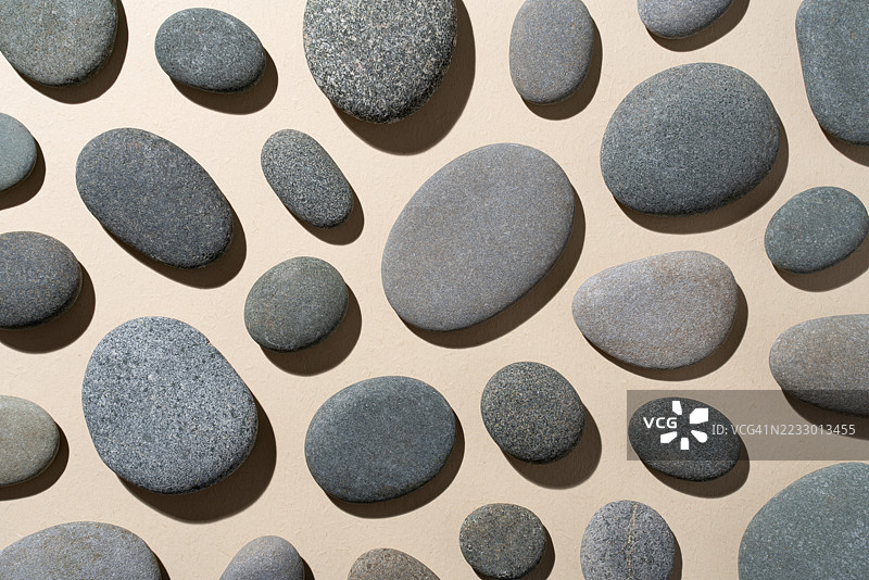 灰色卵石平铺在米色背景上图片素材
