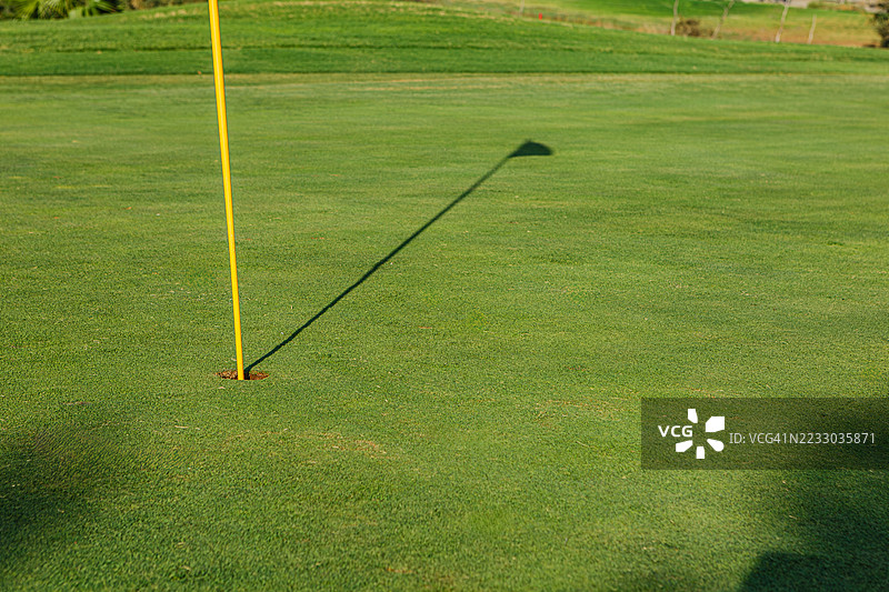 阳光明媚的日子，球场的果岭上有旗帜和阴影图片素材