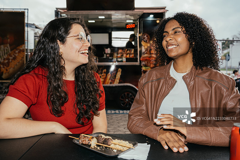 两位女性朋友在餐车享用烤串，享受欢乐时光图片素材