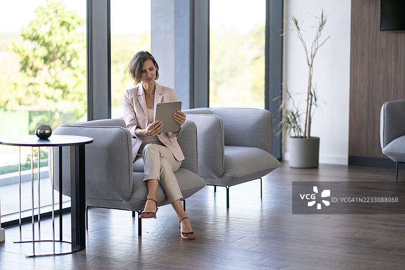 商务女性在现代办公室大堂使用平板电脑图片素材