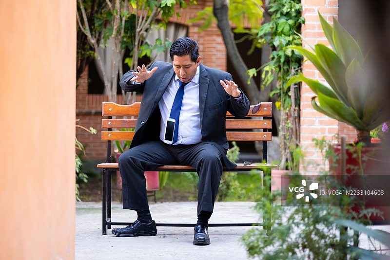 地板上放着一部坏掉的手机，一位商务人士图片素材