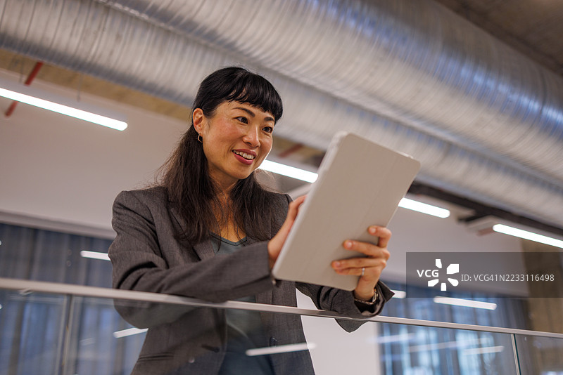 亚洲女商人在现代办公室使用数字平板电脑图片素材