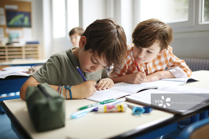 一个孩子在抄写同学的笔记图片素材