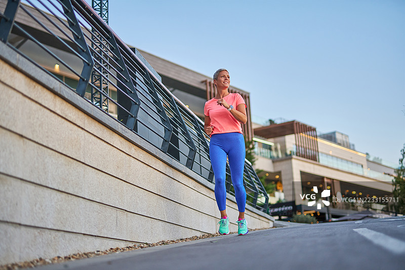 女性在阳光明媚的日子里在城市中慢跑图片素材