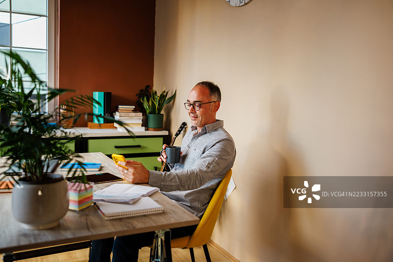 微笑的男人在家办公时享受咖啡休息时间图片素材