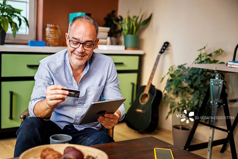 吸引人的男人坐在扶手椅上在线购物图片素材