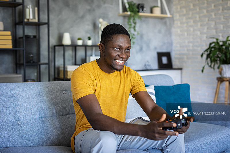 一名男子在舒适的客厅环境中专注于玩游戏手柄的电子游戏图片素材