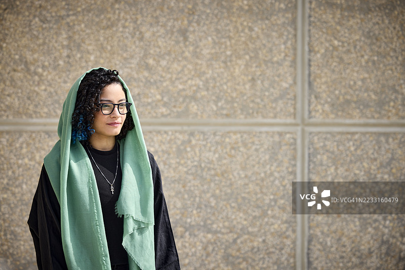 深思的年轻女性站在墙前图片素材