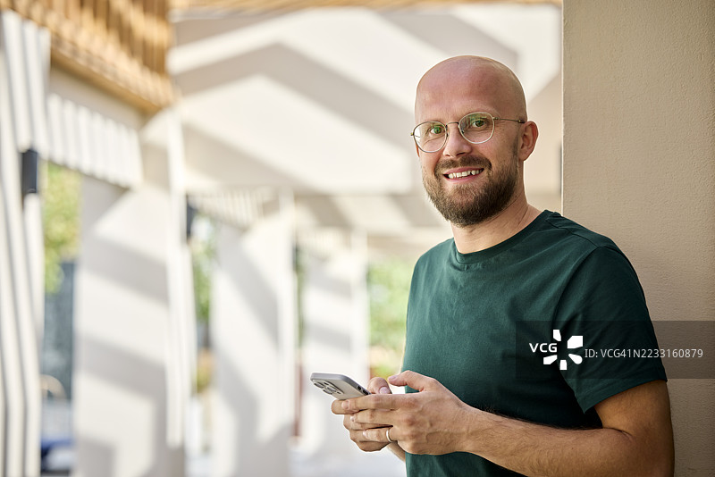 自信的中年商人手持智能手机图片素材