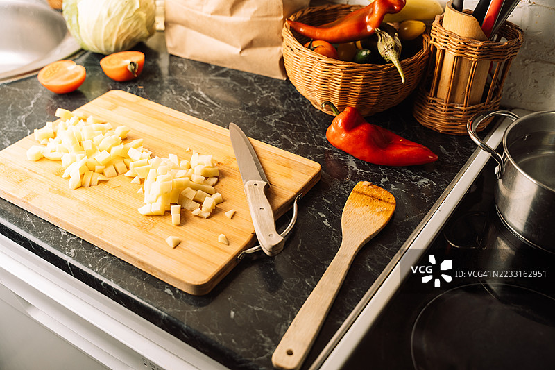 切好的生土豆放在木砧板上，旁边有一把刀图片素材