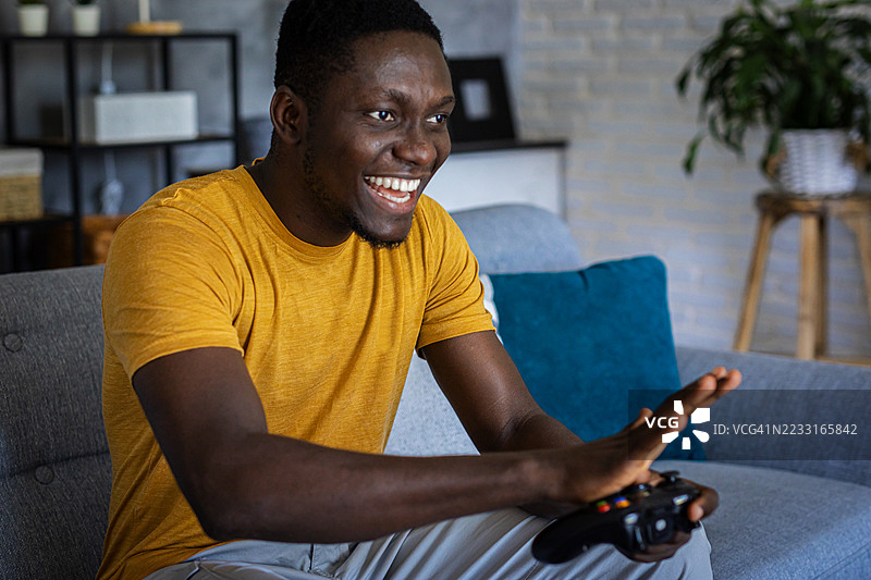 一名男子在舒适的客厅环境中专注于使用操纵杆玩视频游戏图片素材