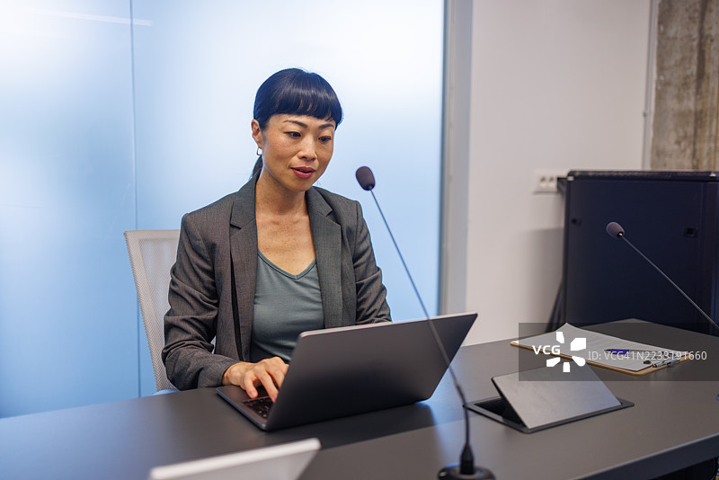 亚洲女商人在会议上使用笔记本电脑和麦克风发言图片素材