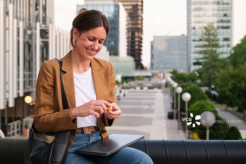 微笑的女商人在城市中休息时涂抹润唇膏或凡士林图片素材