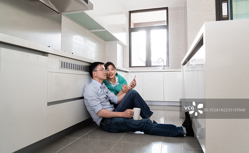 年轻快乐的情侣坐在厨房的地板上图片素材