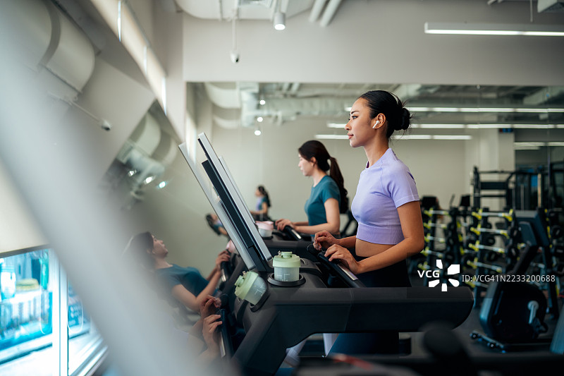健身的亚洲女性在室内锻炼，佩戴耳机图片素材