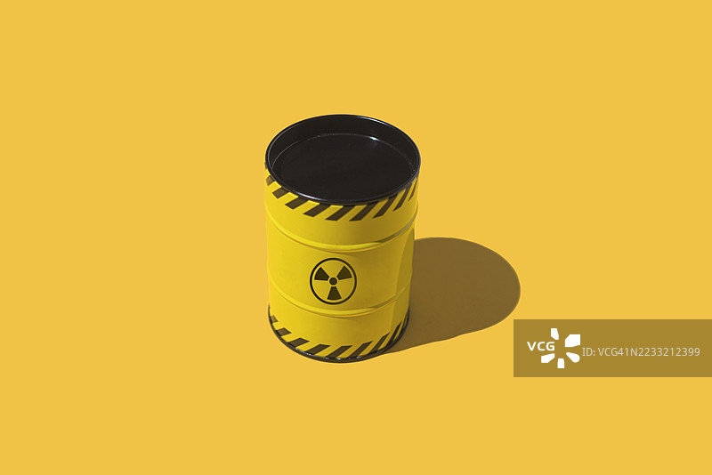 黄色金属桶和黄色背景上的核符号。能源、供应、灾难、斗争、对抗、化学武器、战争、危险和切尔诺贝利。图片素材