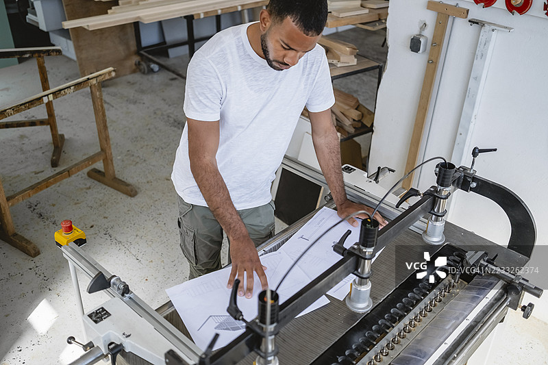 中年多种族木匠在室内操作木工机器图片素材