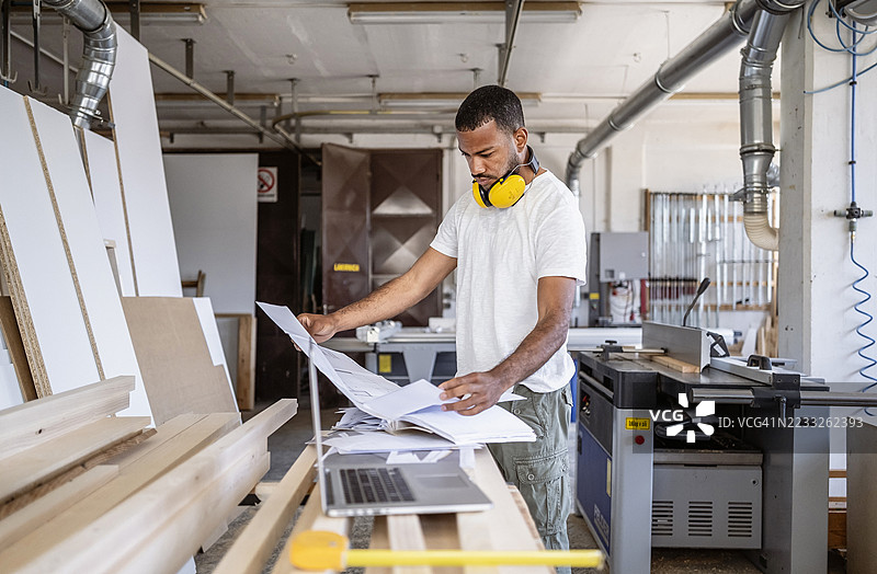 中年男性木匠在明亮的工作坊中查看蓝图图片素材