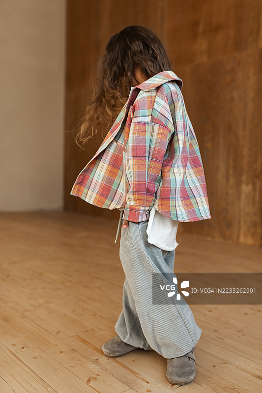 穿着时尚格子服装的孩子在简约木质室内摆姿势图片素材