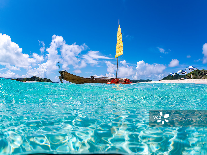 可以看到阳伞、船只，甚至是独特于冲绳的双体船Sabani。拍摄了美丽的白沙滩的一半。还有一群热带鱼。美丽的珊瑚礁和游泳的人们。外岛、座间味岛、慶良間群岛。图片素材