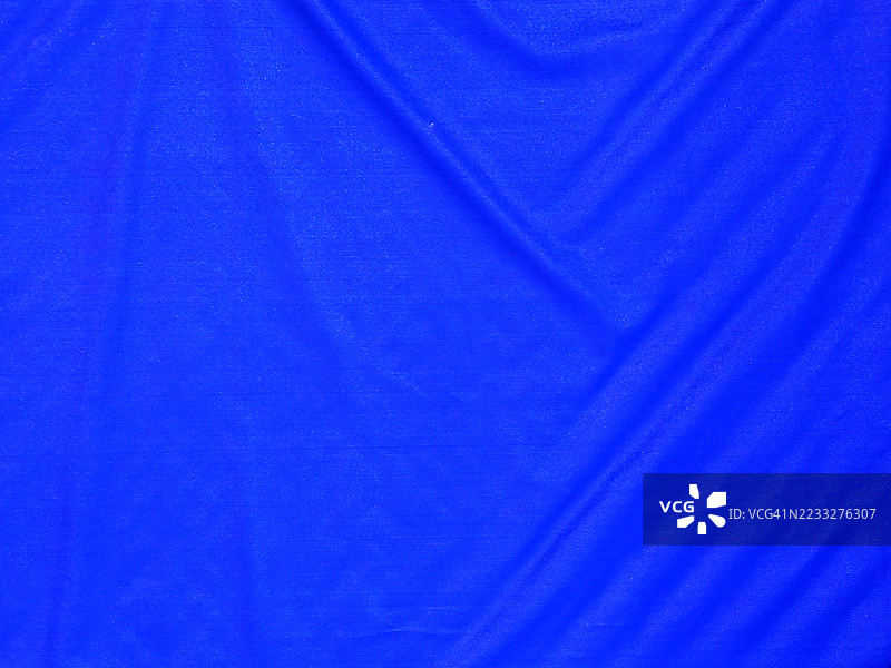 蓝色塑料防水布的特写，带有波纹。粗糙的纹理。阳光。自然色彩。加拿大魁北克省蒙特利尔。图片素材