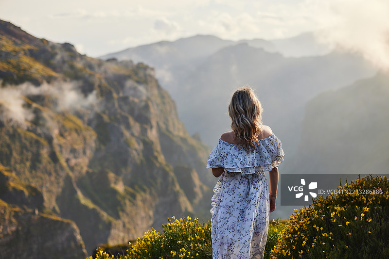 无忧无虑的女人背对着山景。图片素材